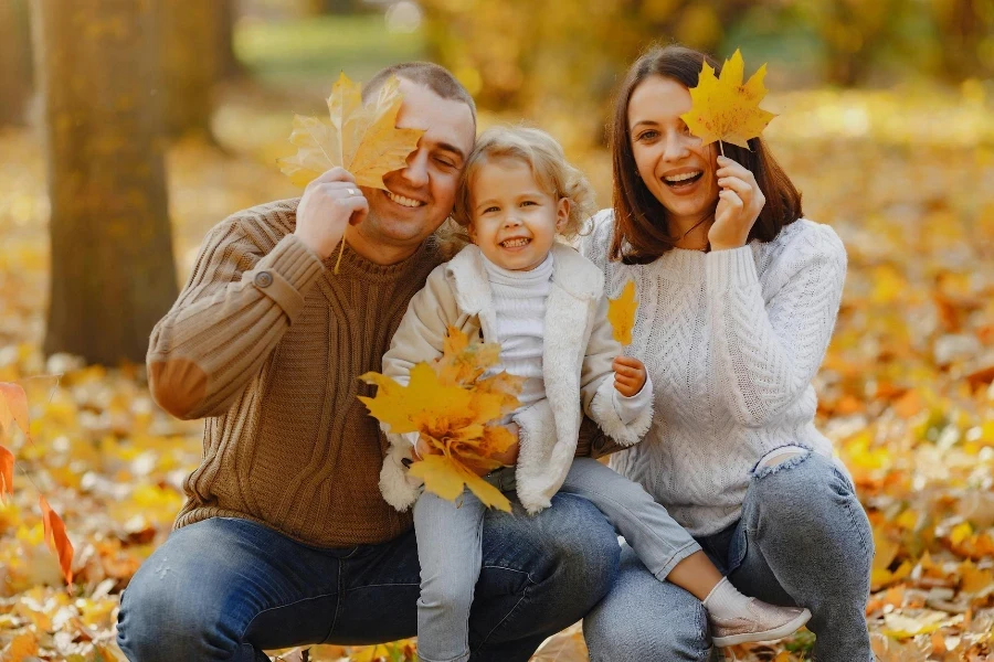 Cheerful family having fun with autumn leaves