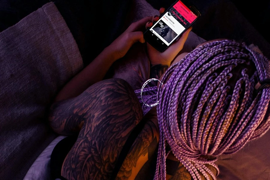 Mulher com cabelo trançado roxo segurando um smartphone Android