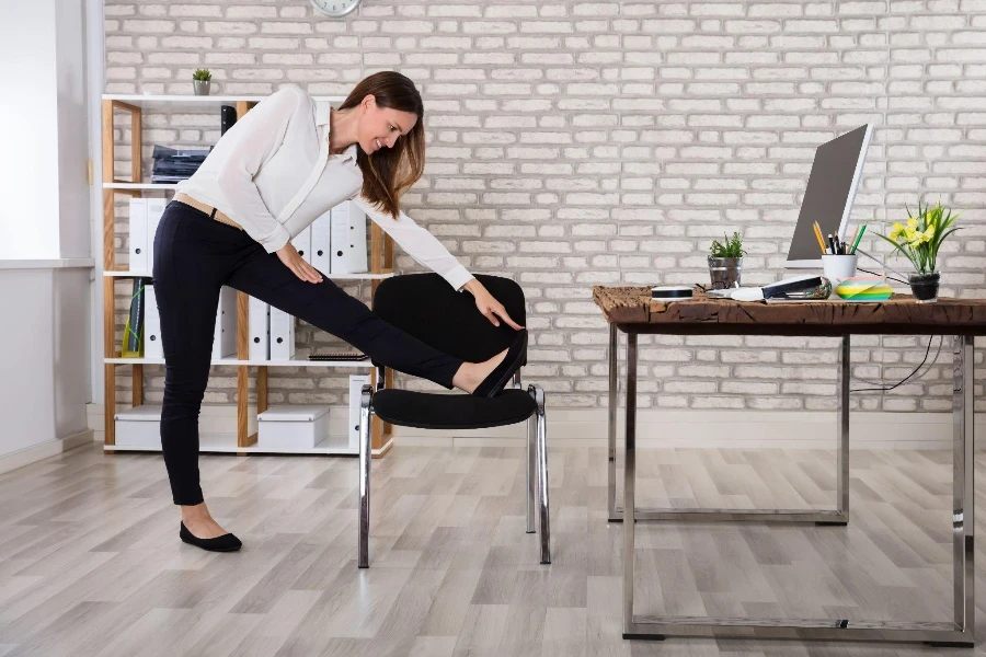 Souriante jeune femme manager assise sur une chaise en s'étirant les bras