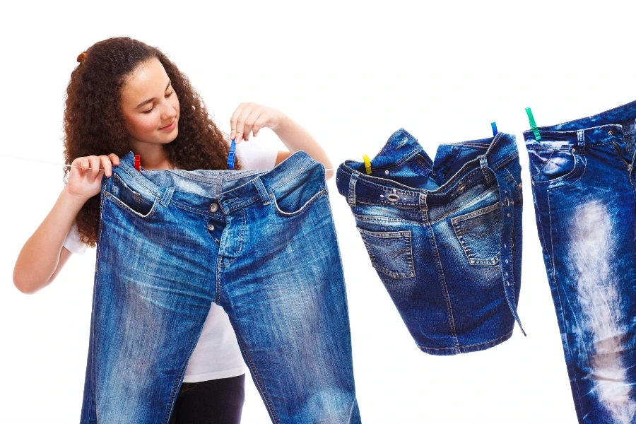 Ragazza che riaggancia i vestiti in denim per asciugarli