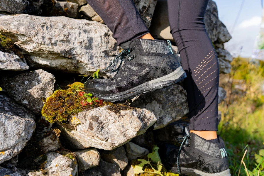 legs in hiking boots of a woman climbing a stone wall
