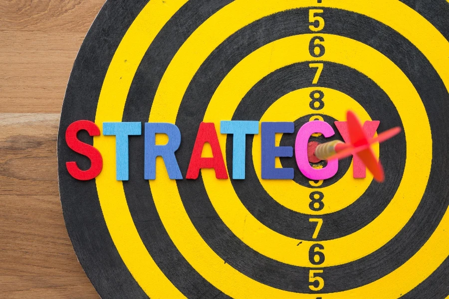Color alphabets STRATEGY on dartboard background with red darts arrow hit center of target.