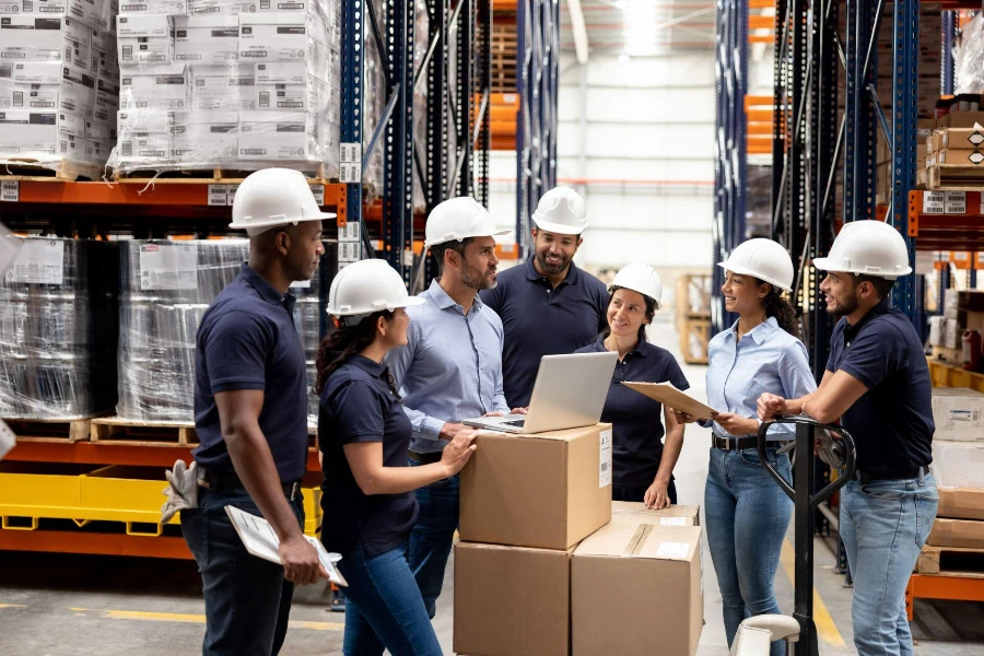 Latin American business manager talking to a group of employees at a distribution warehouse