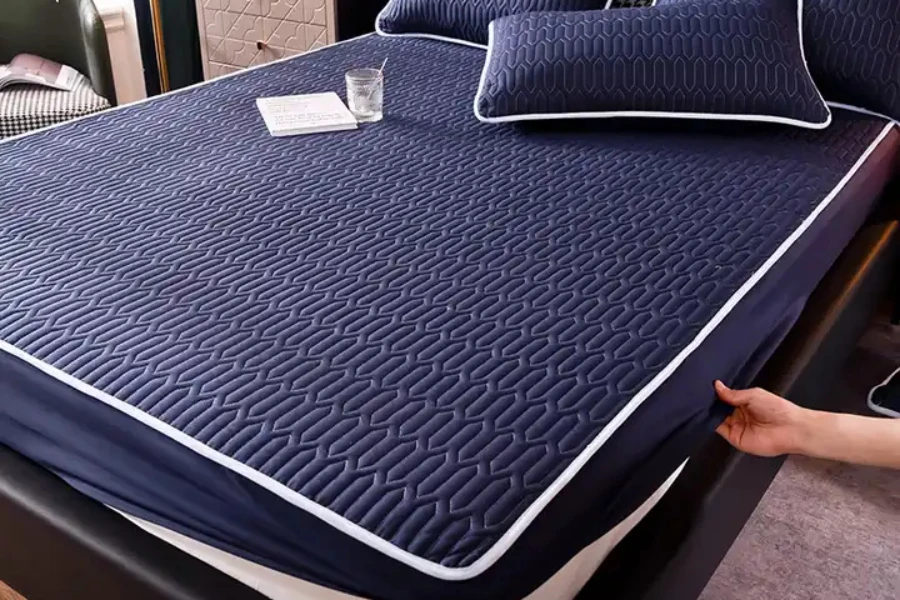 Navy poly-cotton mattress protector and matching pillow protectors on a bed