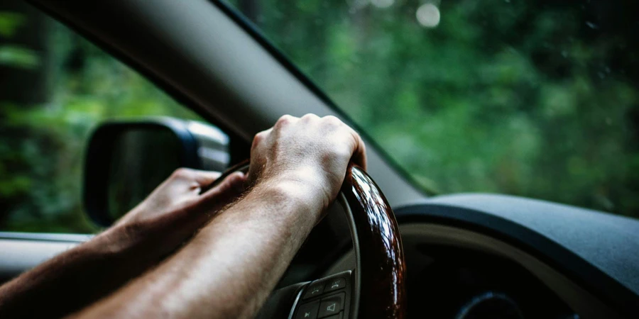 Um homem dirigindo um carro com as duas mãos no volante