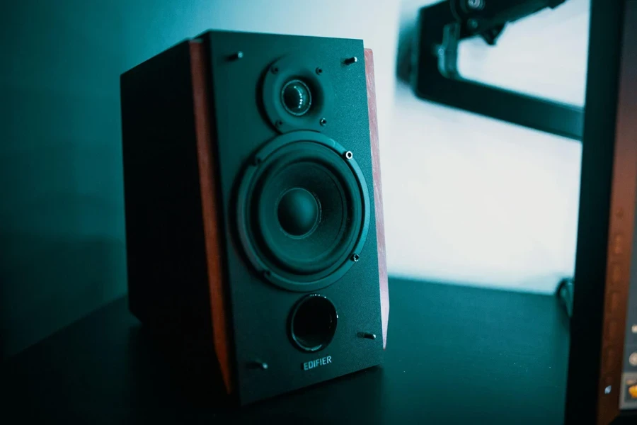 A black Edifier speaker with wood panel sides sits on a desk