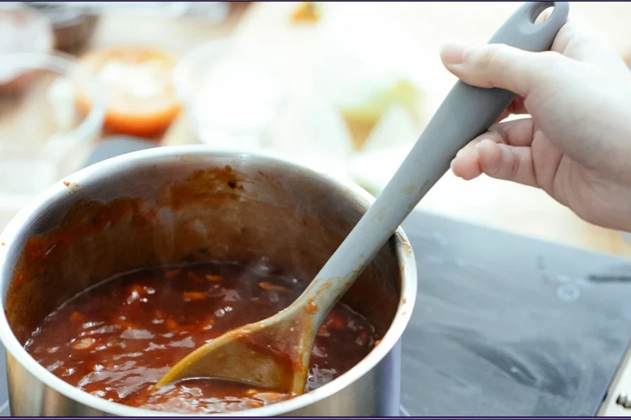 Seorang wanita memasak dengan panci di atas kompor listrik"