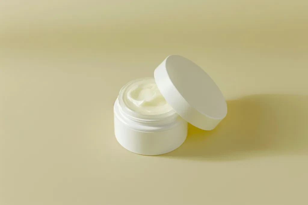 A small white cream jar with the lid open