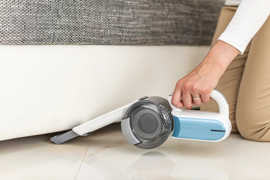 Une femme passe l'aspirateur dans la maison à l'aide d'un aspirateur portable