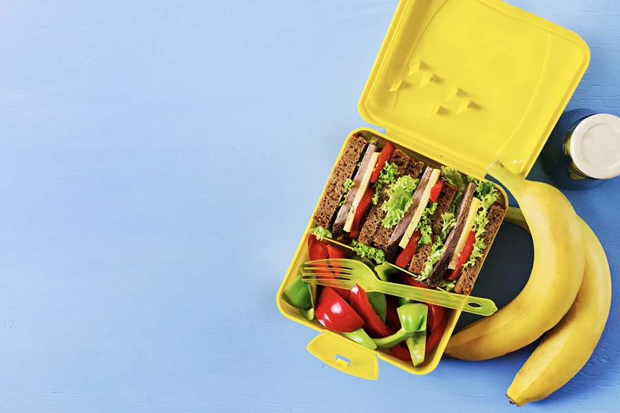 A yellow lunch box with different food compartments