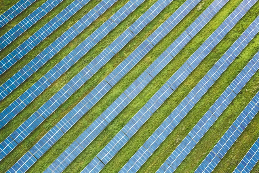 Bir tarla boyunca çapraz olarak çalışan güneş panellerinin havadan çekilmiş görüntüsü