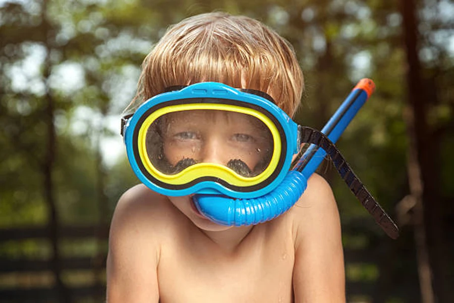 Blond boy wearing blue and yellow goggles with snorkel tube