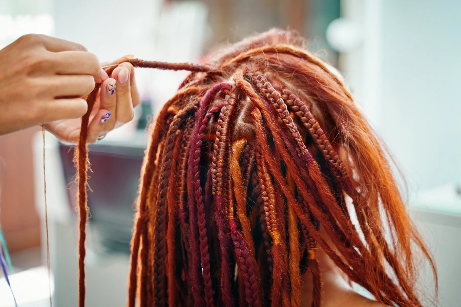Крупным планом процесс плетения косы с цветным канекалоном