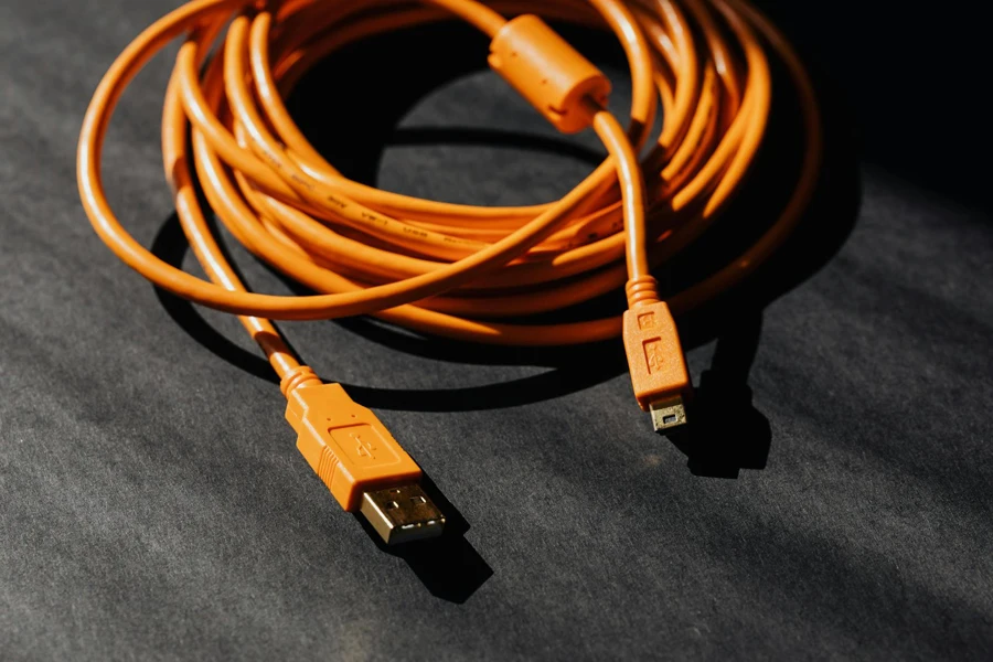 Von oben ein orangefarbenes USB-zu-Micro-USB-Kabel, das zu einem Ring verdreht ist und auf einer schwarzen Tafel platziert ist