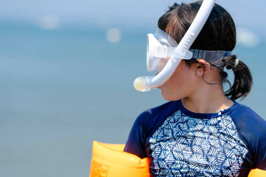 Girl wearing white snorkeling mask with tube on the beach