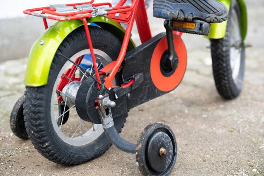 Eğitim tekerlekleri ve sarı bisiklet çamurlukları olan çocuk bisikleti