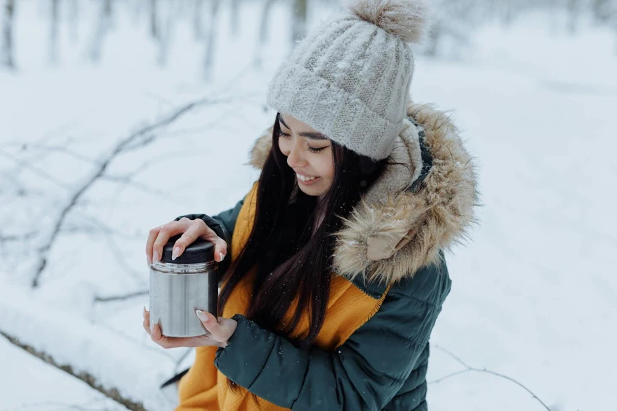 Señora sosteniendo un frasco de comida al vacío en la nieve.