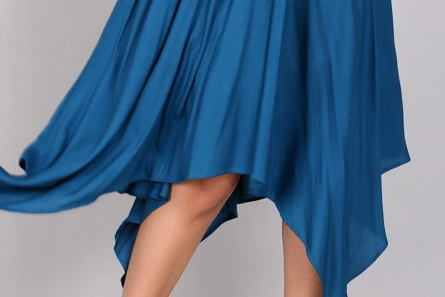 Lady showcasing a blue, draping sundress with an asymmetrical hem