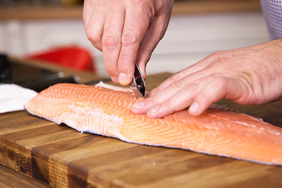 Homem usando uma pinça de espinha de peixe em um filé