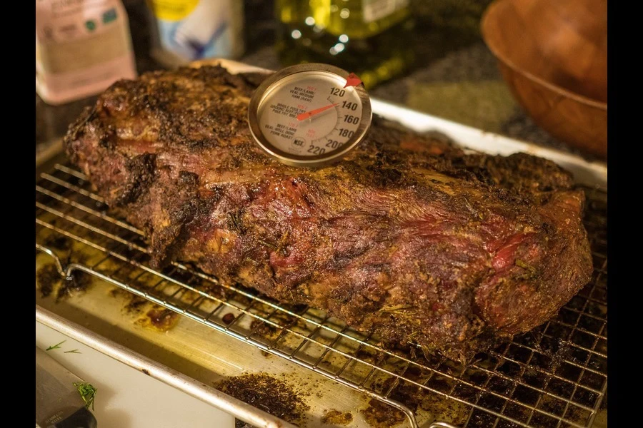 Termómetro para carne mantenido sobre un trozo de carne caliente.