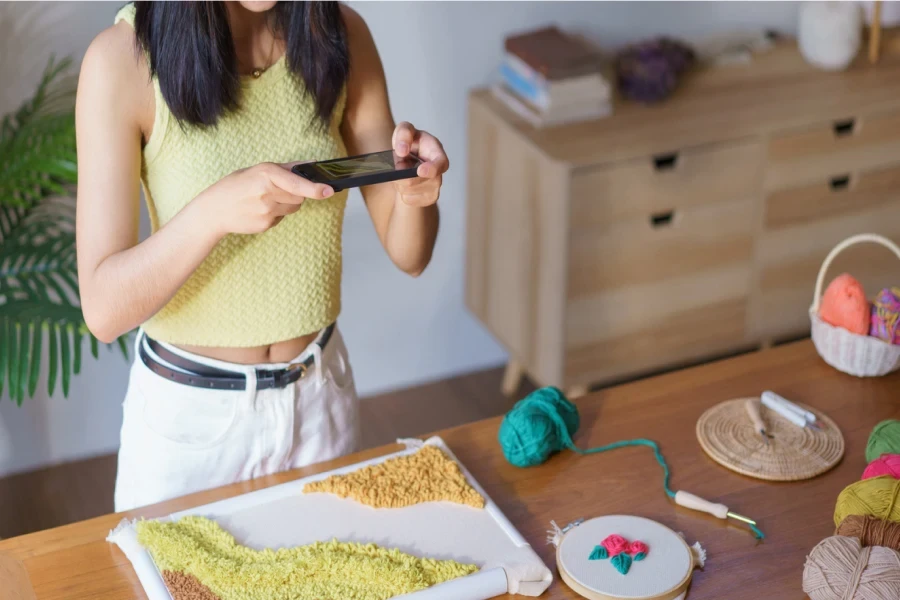 Concept de couture, les femmes utilisent un téléphone pour prendre des photos de performances de bricolage de cadre de poinçon de tissu de broderie.