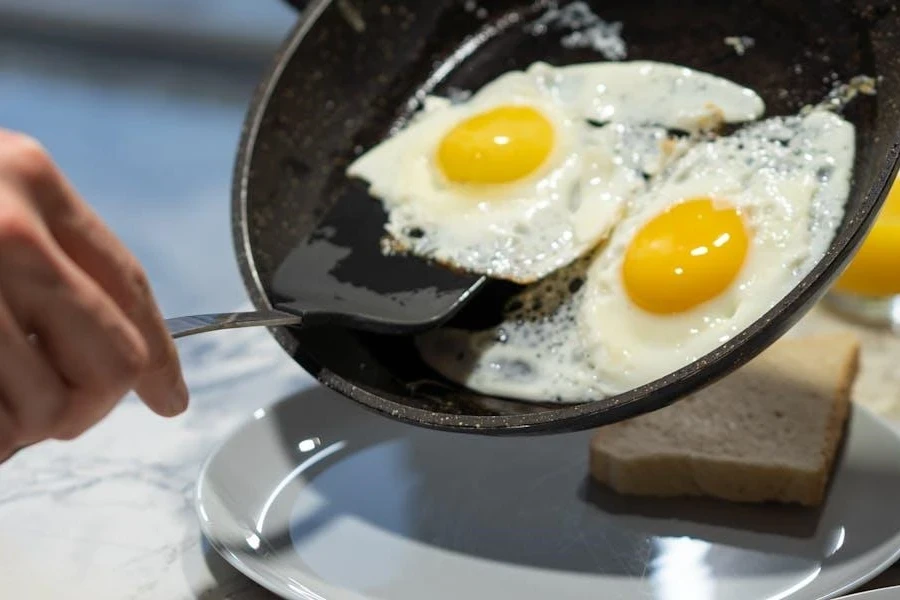 Persona che usa una spatola per rimuovere le uova da una padella