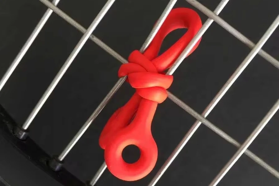 Amortecedor de corda vermelha amarrado em cordas na raquete de tênis