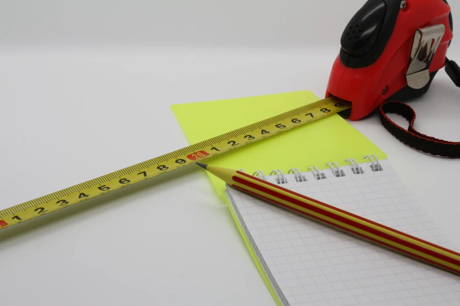 Tape measure, notebook, and pencil on a white background