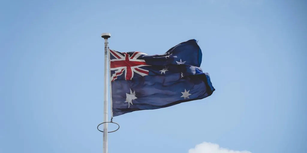 Açık mavi gökyüzüne karşı zarif bir şekilde dalgalanan Avustralya bayrağı
