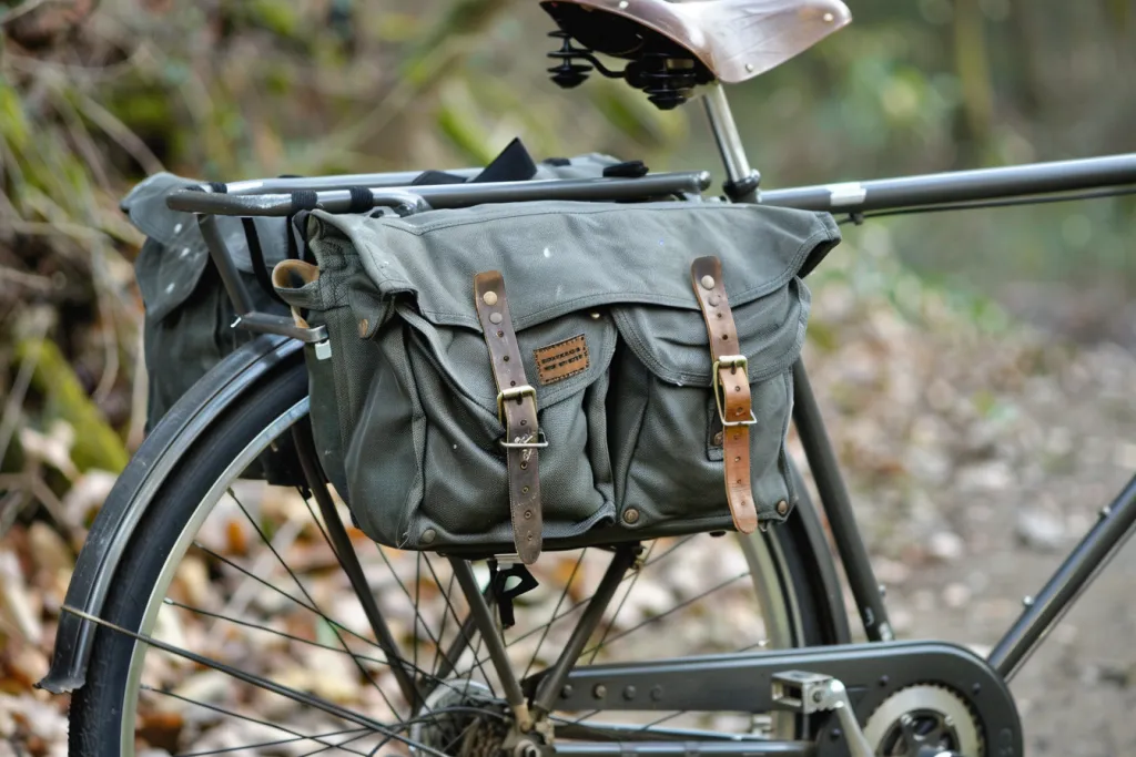 The bike bag is on the back of an old gray bicycle with two large bags and one small side pannier