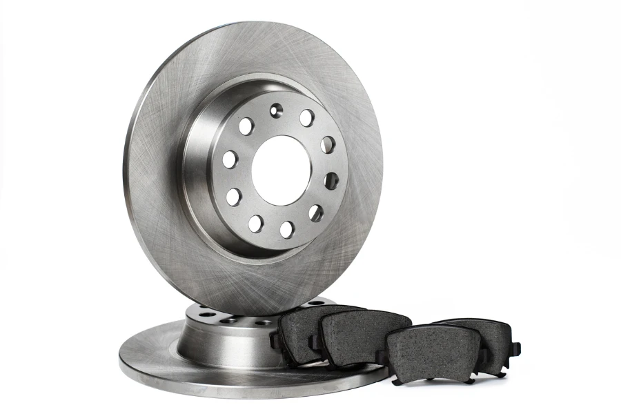 Two new brake discs and a set of brake pads stacked in a row on a white background