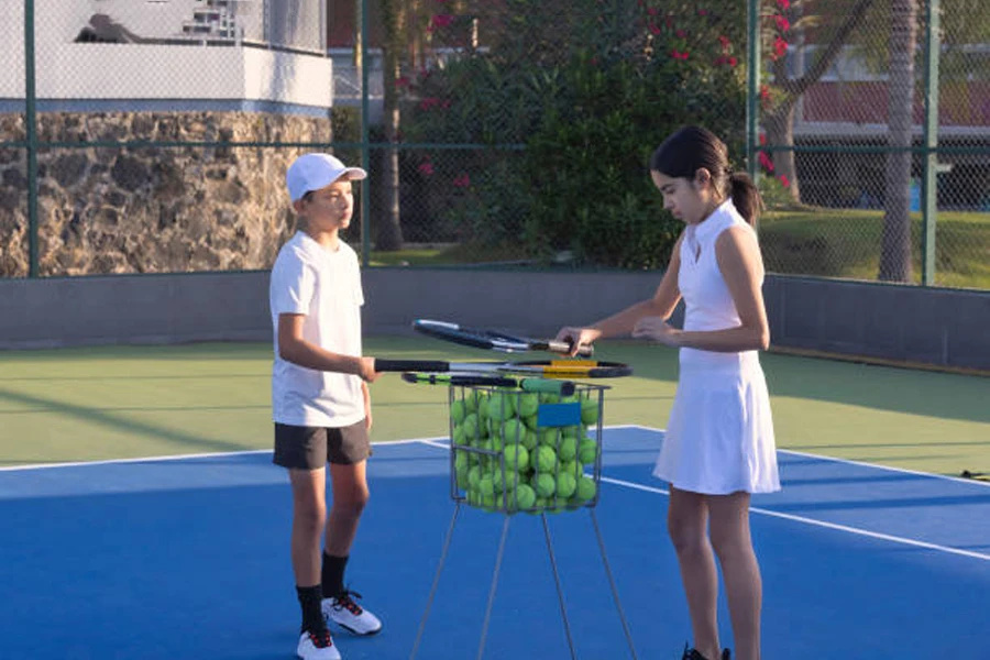 Zwei Tennisspieler werfen Bälle in einen Trichter
