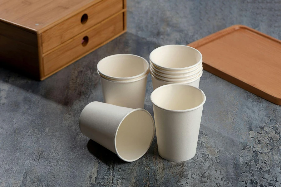 Белые бумажные стаканчики и деревянная коробка на столе