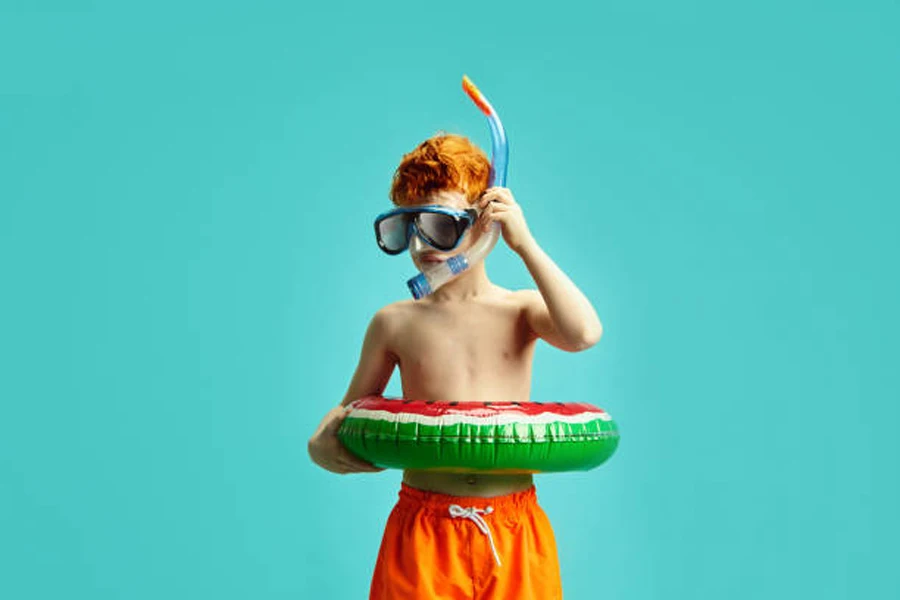 Young boy wearing snorkeling mask and watermelon floatation ring