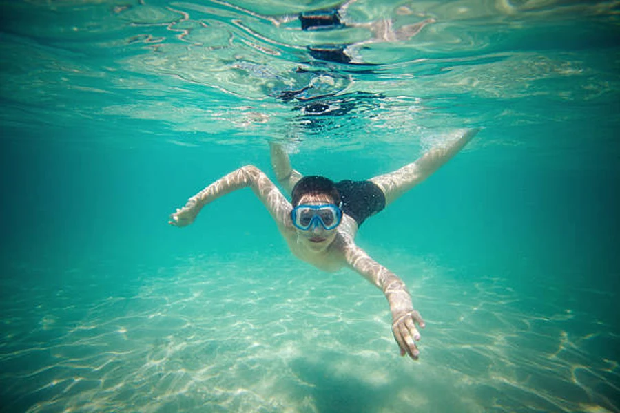 Young child swimming underwater wearing bright snorkeling mask