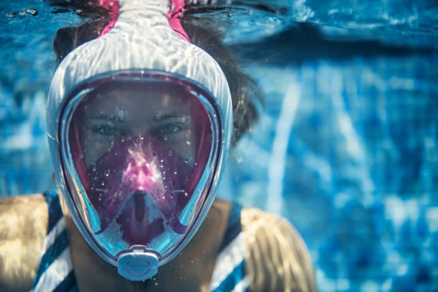 Молодая девушка в бело-розовой полнолицевой маске для подводного плавания