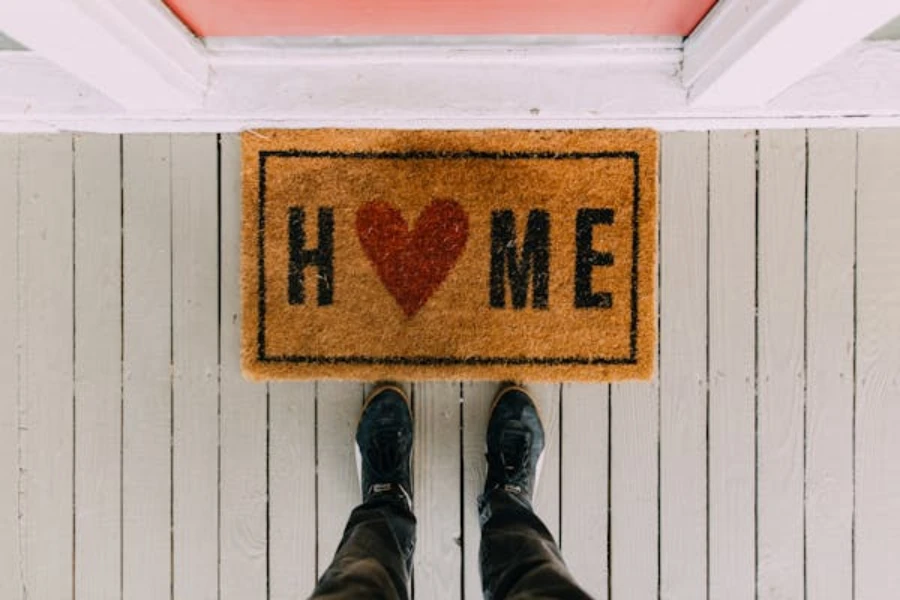 A person standing beside a personalized doormat