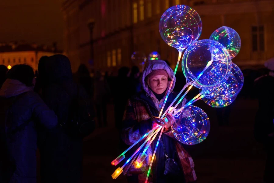 Una mujer vendiendo globos LED por la noche.