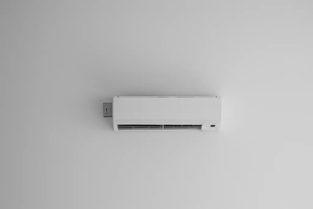 A white wall with an air conditioner hanging on the side