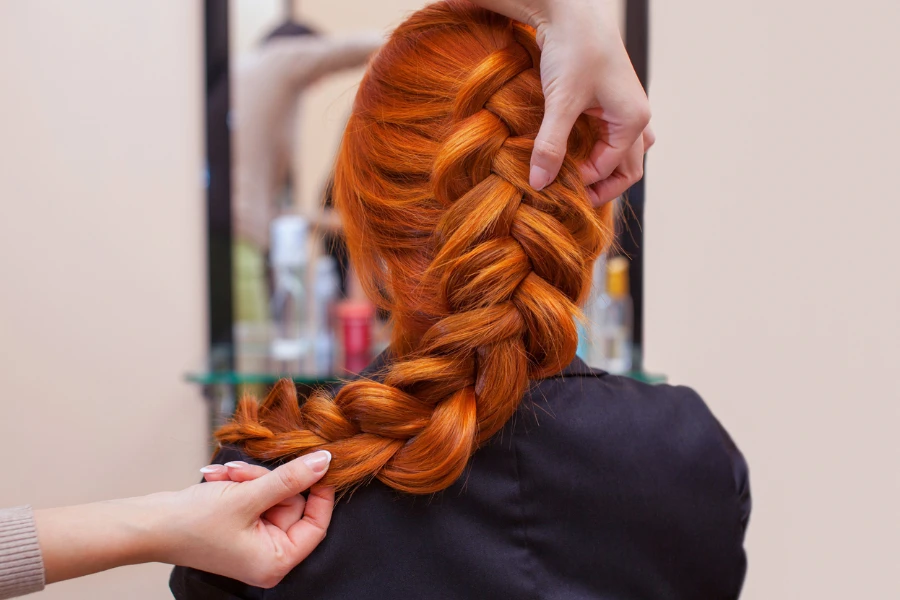 hairdresser weaves a French braid
