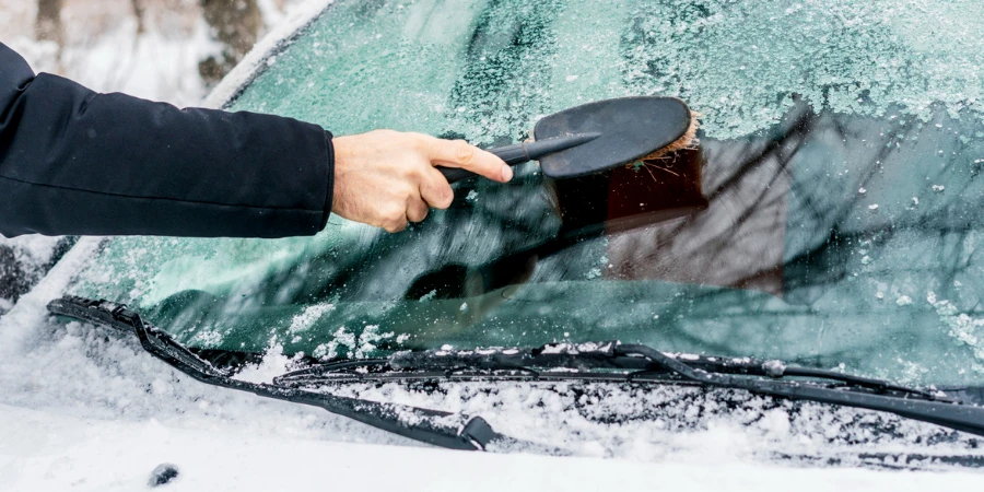 hand cleaning up windscreen from snow
