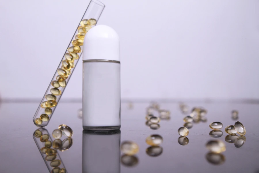 una bottiglia bianca vuota messa su un tavolo di vetro con pillole vitaminiche sul pavimento e in un tubo scientifico