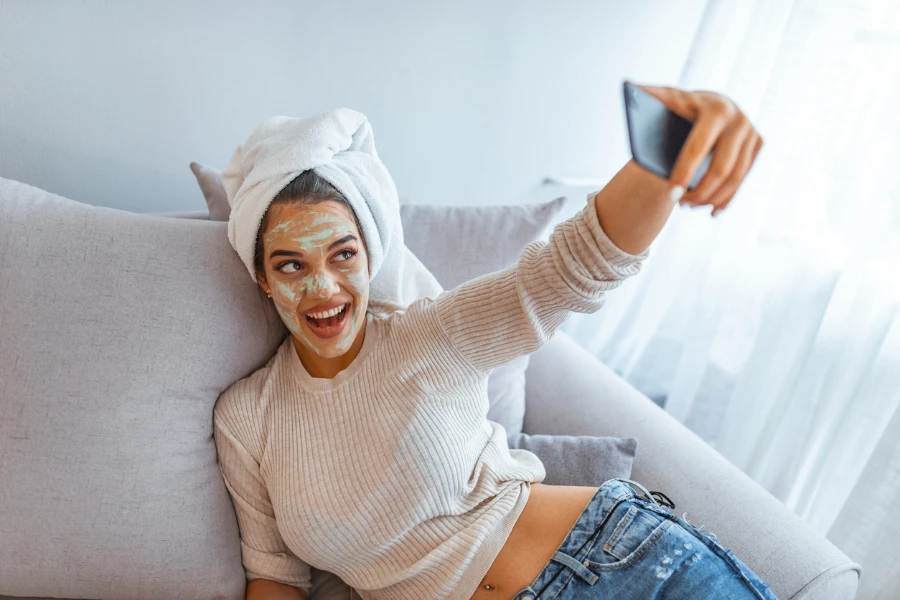 Feche a selfie de uma linda mulher feliz depois do banho com uma toalha na cabeça