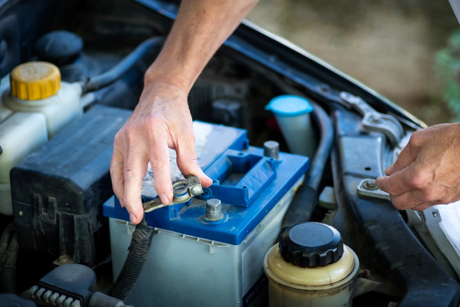 Manusia menghubungkan baterai mobil ke kendaraan dengan baterai traktor kunci pas