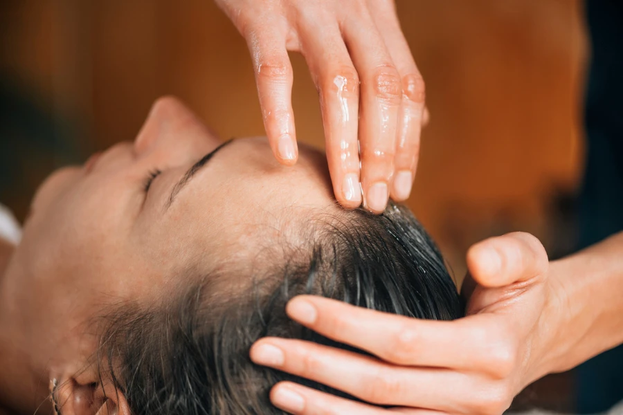 Mulher desfrutando de tratamento com óleo ayurvédico para cabelos saudáveis