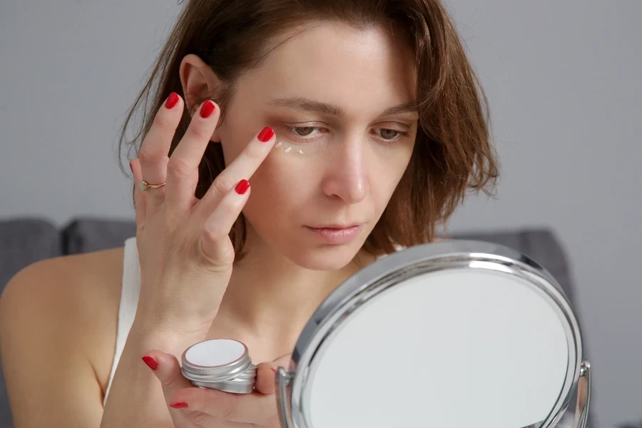 Woman using skin care products in front of the mirror at home
