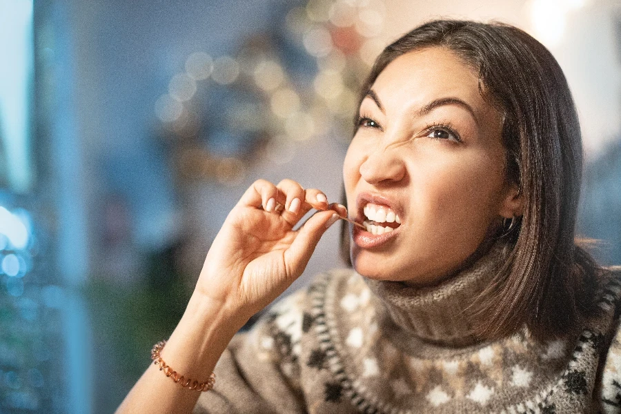 Una donna divertente sorride, fa l'occhiolino e si prende i denti con uno stuzzicadenti al primo appuntamento