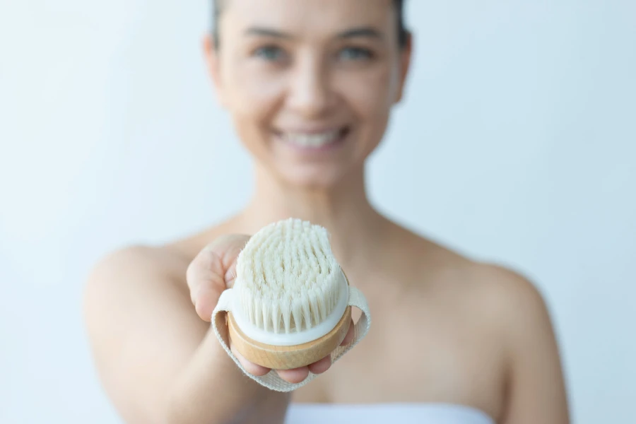 A parte intermediária da mulher caucasiana está mostrando escova seca com um sorriso cheio de dentes para a câmera