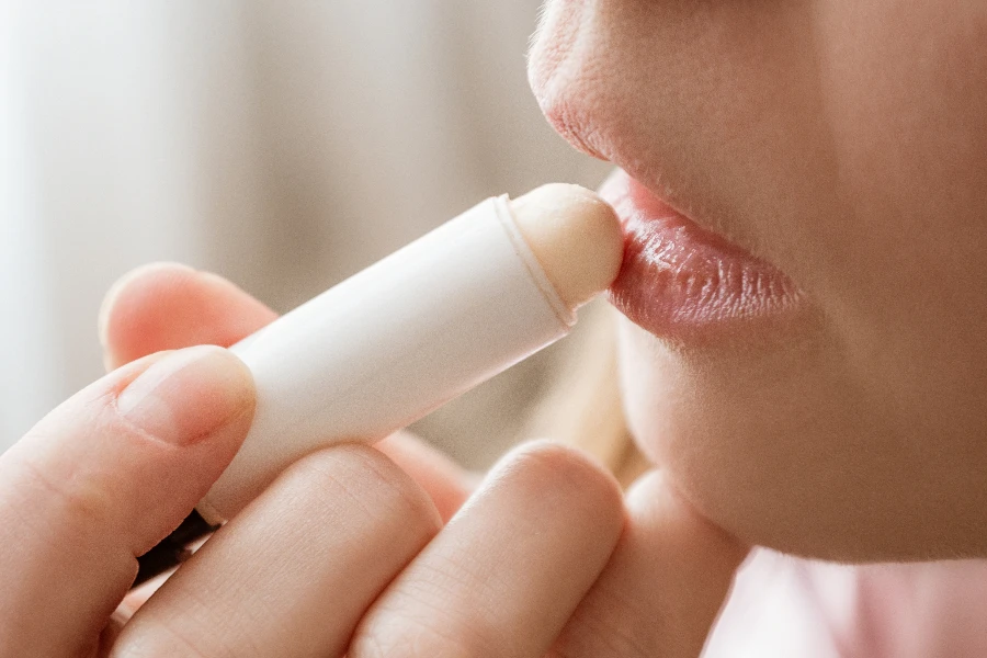 Une jeune femme applique un baume hydratant sur ses lèvres