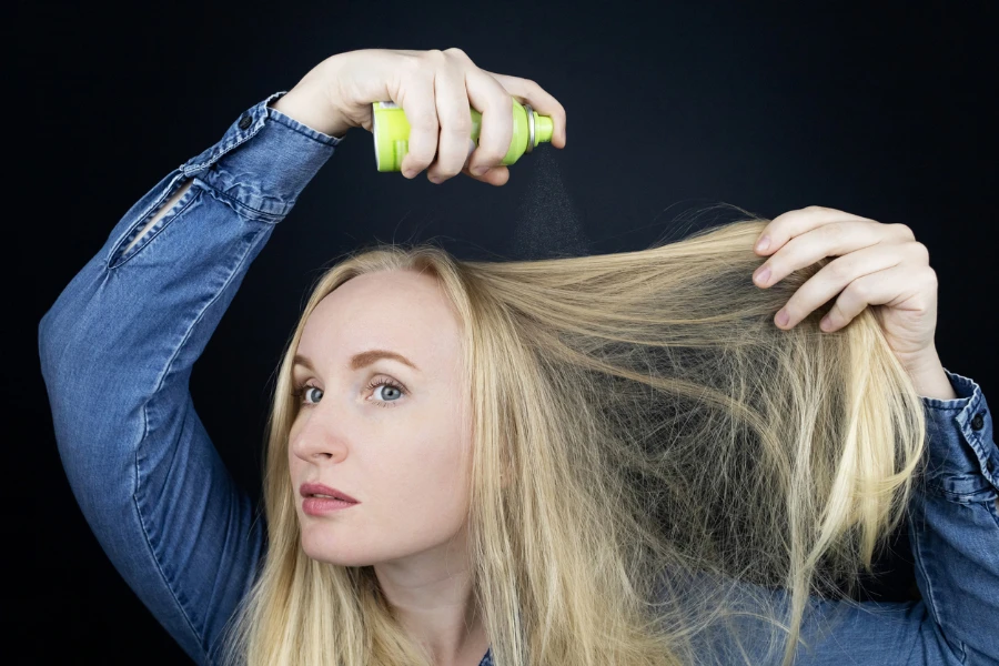 Blondes Mädchen sprüht Shampoo auf ihr Haar